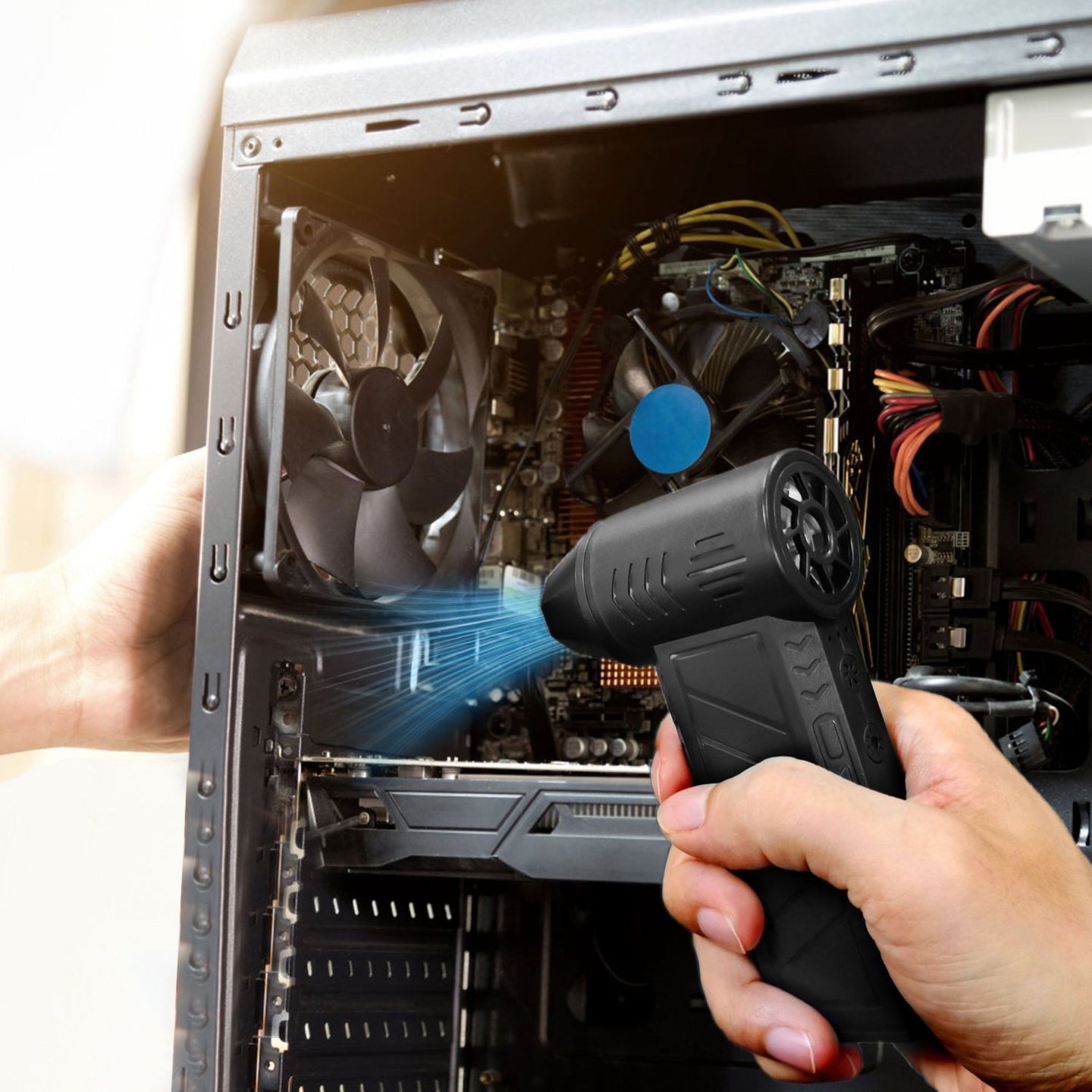 Person cleaning inside a computer case with a handheld air duster.